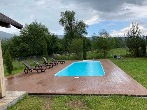 a swimming pool on a wooden deck with chairs around it at Вілла Софі in Verkhovyna