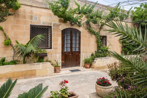 a building with a door and some plants and flowers at Ta' Bertu Host Family Bed & Breakfast in Ħal Far