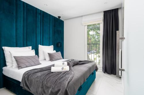 1 dormitorio con 1 cama grande y pared azul en EL Apartments - Solaris, en Poznan