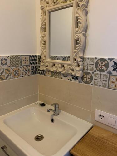 uma casa de banho com um lavatório e um espelho na parede em Dos Leones em Vejer de la Frontera