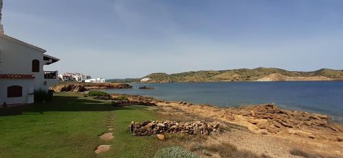 a building next to a body of water at Apto POBLET by MENORCAHOST - Vistas únicas al mar en Playas de Fornells in Es Mercadal