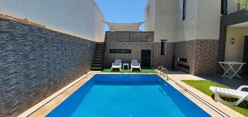 a swimming pool with two chairs and a building at Villa Nour in Fès