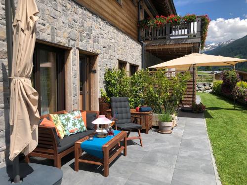 a patio with chairs and a table and an umbrella at Alpenburg Bergparadies Apartments in Wald am Arlberg