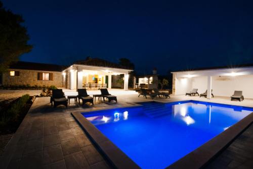 a swimming pool in a backyard at night at Luxury Villa Nature with heated private pool, sauna & fire pit, a short walk to the beach in Milna