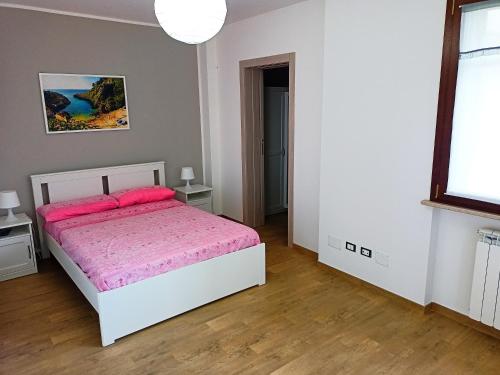 1 dormitorio con 1 cama blanca con sábanas rosas en Casa vacanze Fabrizio, en Andrano