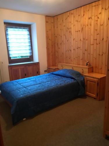 a bedroom with a blue bed and a window at Appartamenti Il Castello in Saint-Pierre