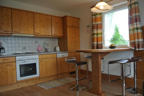 a kitchen with wooden cabinets and a table and stools at Landhaus Neubauer in Millstatt