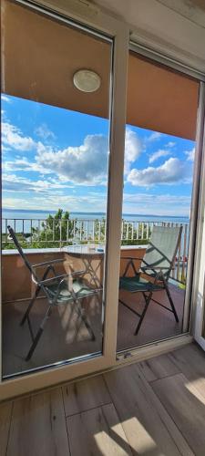 a balcony with a chair and a view of the ocean at Panoráma Gold Wellness Apartman in Siófok