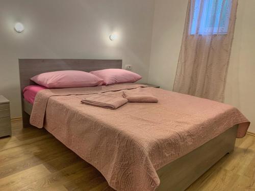 a bed with pink pillows and a pink blanket at Apartment Lea Mataija in Novi Vinodolski