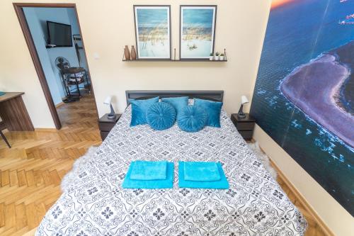 a bedroom with a bed with two blue pillows at Apartament z jacuzzi in Hel