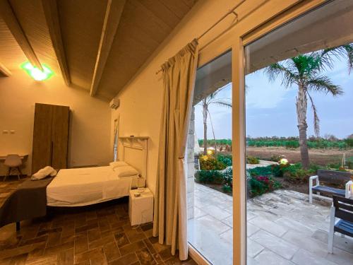 a bedroom with a bed and a patio with palm trees at PODERE CARAFA in Nardò