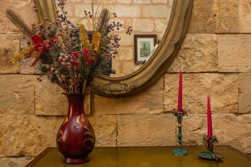 a vase with flowers on a table in front of a mirror at Ta' Bertu Host Family Bed & Breakfast in Ħal Far