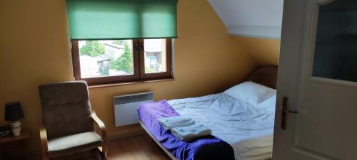 - une chambre avec un lit, une chaise et une fenêtre dans l'établissement Pokoje i kwatery w Augustowie, à Augustów