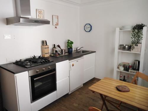 uma cozinha com armários brancos, um fogão e uma mesa em In San Frediano B&B em Florença