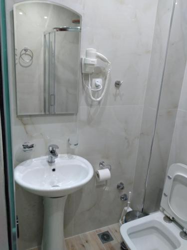 a white bathroom with a sink and a toilet at Ηotel Della in Parga