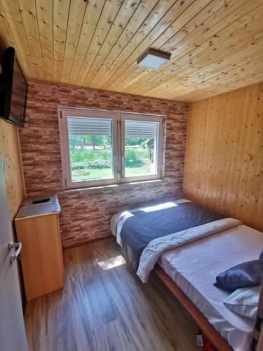 a bedroom with a bed and two windows at Sára Vendégház 2 in Szentes