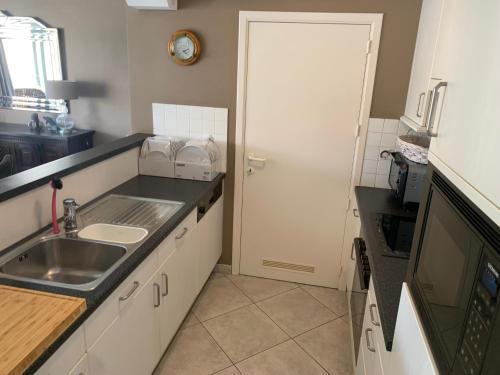 a small kitchen with a sink and a door at Boothuis Ter Vaart in Blankenberge