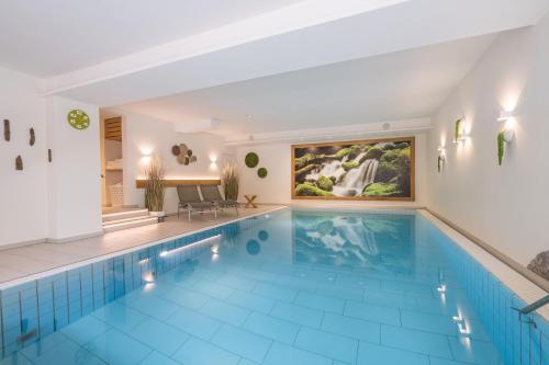 a large swimming pool with a blue tile floor and a large painting at Hotel garni Gerberhof ***S in Oberstdorf
