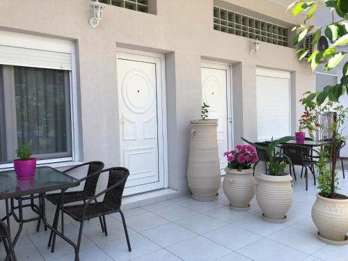a patio with tables and chairs and potted plants at VASILEVI STUDIOS in Nea Kalikratia