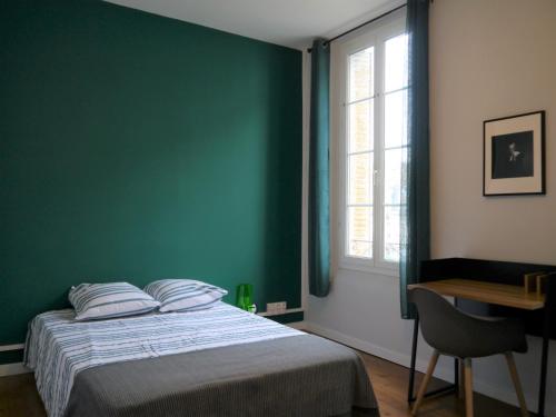 Schlafzimmer mit grünen Wänden und einem Bett mit einem Schreibtisch in der Unterkunft Appartement le Flatiron - 4 chambres in Tarbes