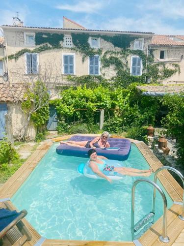 un homme et une femme dans une piscine dans l'établissement Chambres et table d'hôtes Au Brabo, à Mormoiron