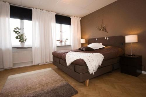 a bedroom with a large bed and two windows at Stay Apartment Hotel in Karlskrona
