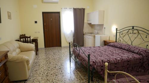a bedroom with a bed and a couch and a kitchen at Masseria Lama D'impisa in Fasano