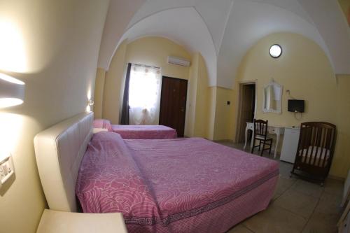 a bedroom with two beds with purple covers in a room at Masseria Lama D'impisa in Fasano