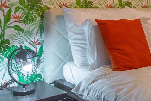 a bed with an orange pillow and a lamp on a table at Apartmani Maximilian in Čukarica