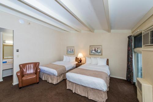 ein Hotelzimmer mit 2 Betten und einem Stuhl in der Unterkunft Windjammer Lodge in Ogdensburg