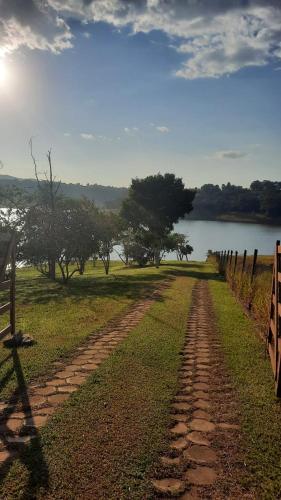 a dirt road next to a fence and a lake at Chalé Represa Recanto Varanda do Sol in Joanópolis