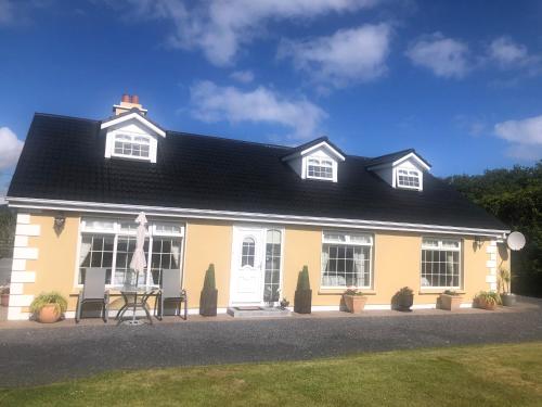 a yellow house with a black roof at Murrayville B&B in Achill Sound