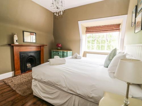 a bedroom with a large white bed and a fireplace at Bearnock Lodge in Inverness