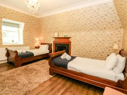 a bedroom with two beds and a fireplace at Bearnock Lodge in Inverness