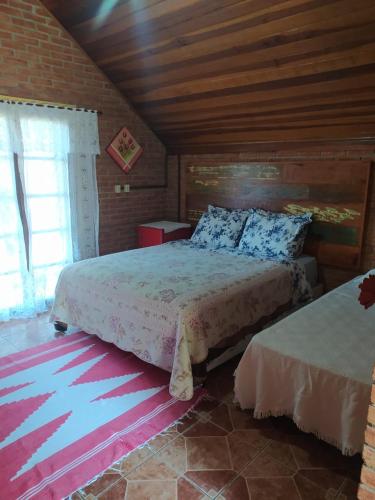 a bedroom with two beds and a window at Chalé Represa Recanto Varanda do Sol in Joanópolis