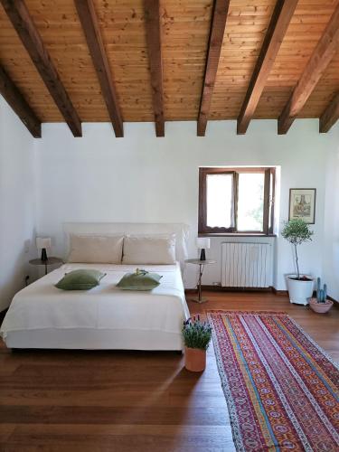 a bedroom with a white bed and a wooden ceiling at Villa Rustico in Viboldone