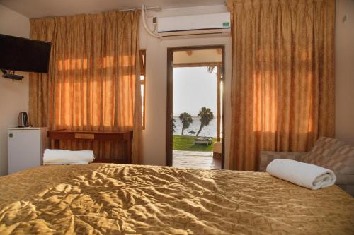 1 dormitorio con 1 cama grande y puerta corredera de cristal en Hotel El Condor, en Paracas