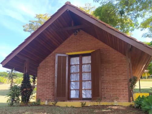 a small brick house with a large window at Chalé Represa Recanto Varanda do Sol in Joanópolis