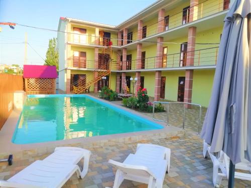 a hotel with a pool and two chairs and a building at Solnechnaia Dacha in Zatoka