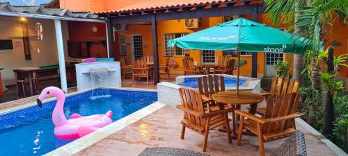 a pool with a table and a pink swan in it at Pousada Sao Paulo in Vila Muriqui