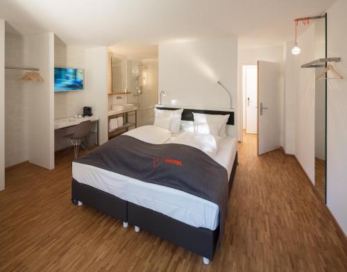 a bedroom with a large bed and a desk at V-Hotel in Bonn