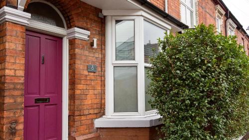 a purple door and a window on a brick house at 8 Samuel Street in Crewe