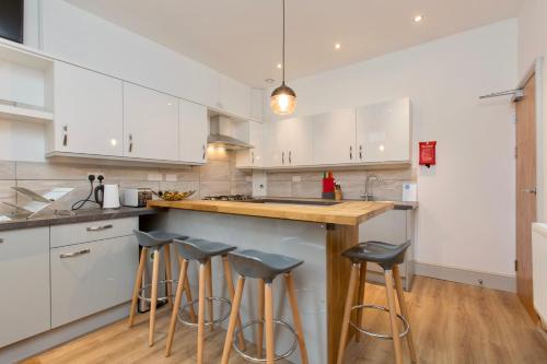 a kitchen with white cabinets and bar stools at 8 Samuel Street in Crewe