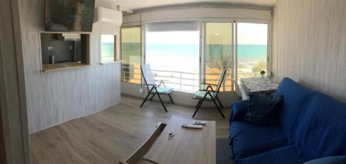 een woonkamer met een blauwe bank en uitzicht op de oceaan bij Frente al mar, a 10 metros de la playa, vistas increíbles del mar, reformado 2021 !!! in El Campello