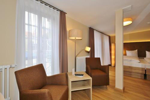 a hotel room with a bed and a chair and a table at Hotel Theophano in Quedlinburg