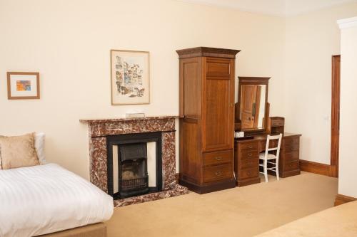 a bedroom with a fireplace and a bed and a dresser at Springkell in Eaglesfield