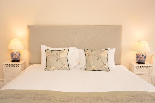 a bedroom with a white bed with two lamps at Springkell in Eaglesfield