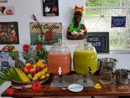 a table with two glasses of juice and a bowl of fruit at Pousada Sao Paulo in Vila Muriqui