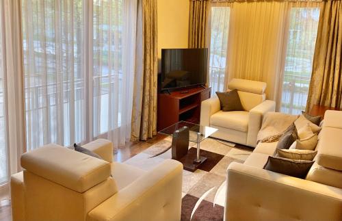 a living room with white furniture and a tv at A01 Sétány-Silverine Apartmanház-Őrzött parkolóval in Balatonfüred