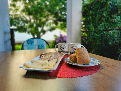 a table with a plate of cheese and bread and cups at Apartment Adriana in Seget Vranjica